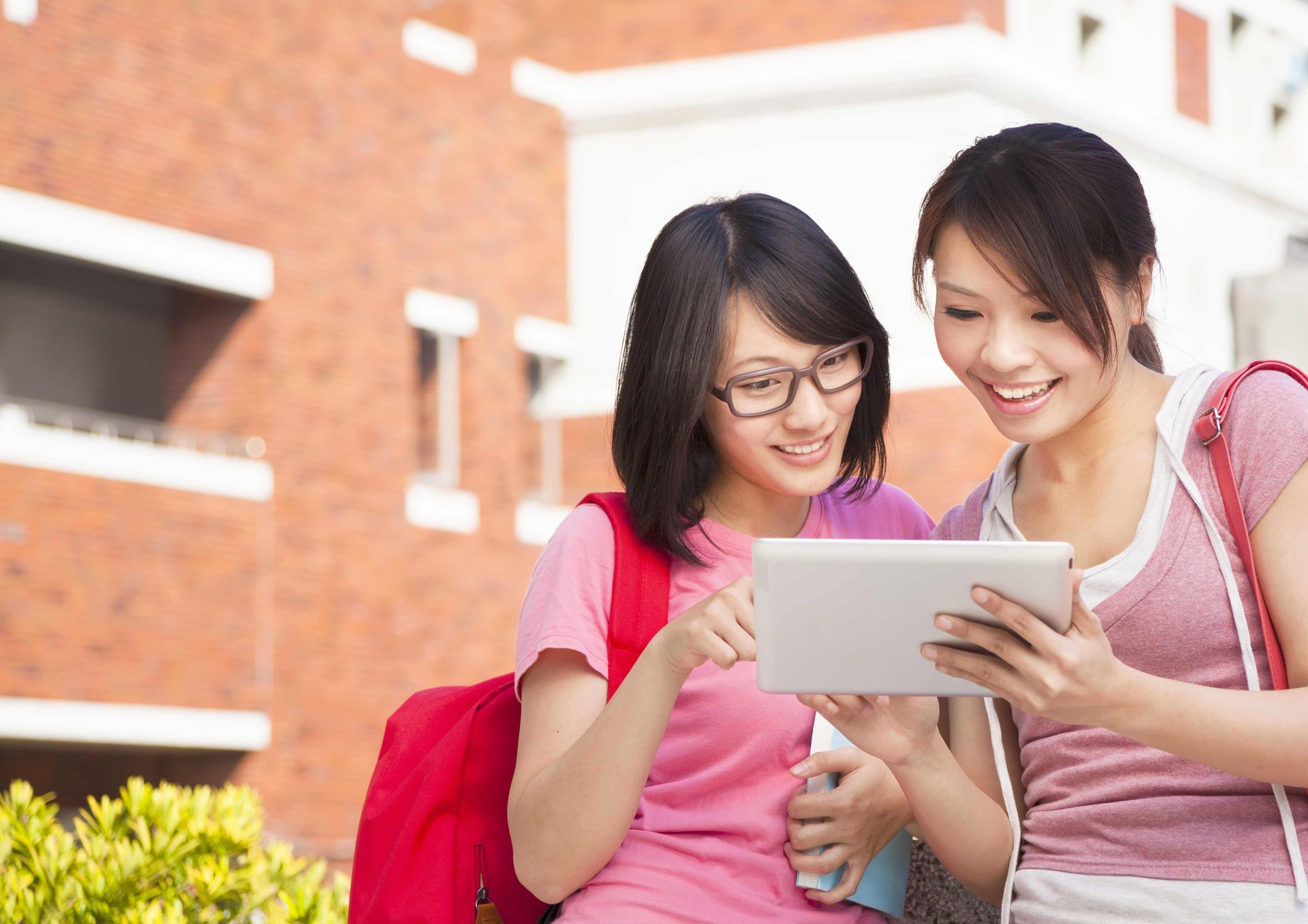 Students with tablet outside university building